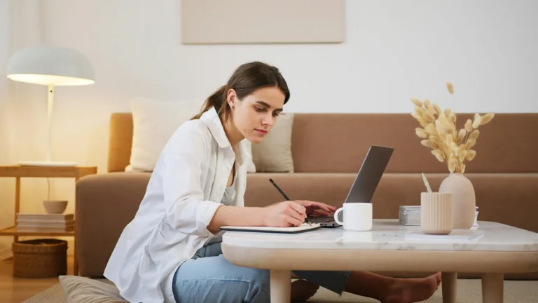 Student studying for the SAT at home in Europe, taking notes with a laptop